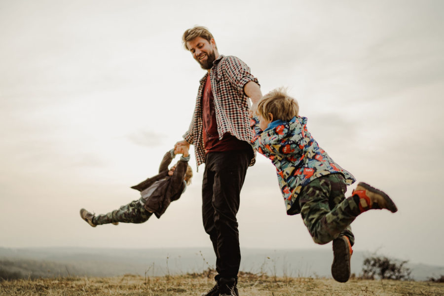 Gemeni băieți se învârt cu tati. Copii jucăndu-se. Joacă împreună. Fotografie de familie